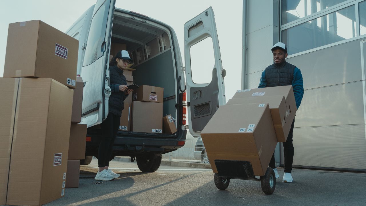 Two people unloading boxes from a van 